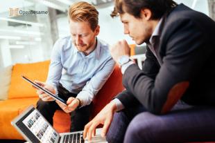 Two business professionals sitting on an orange couch while looking at OpenSesame courses 